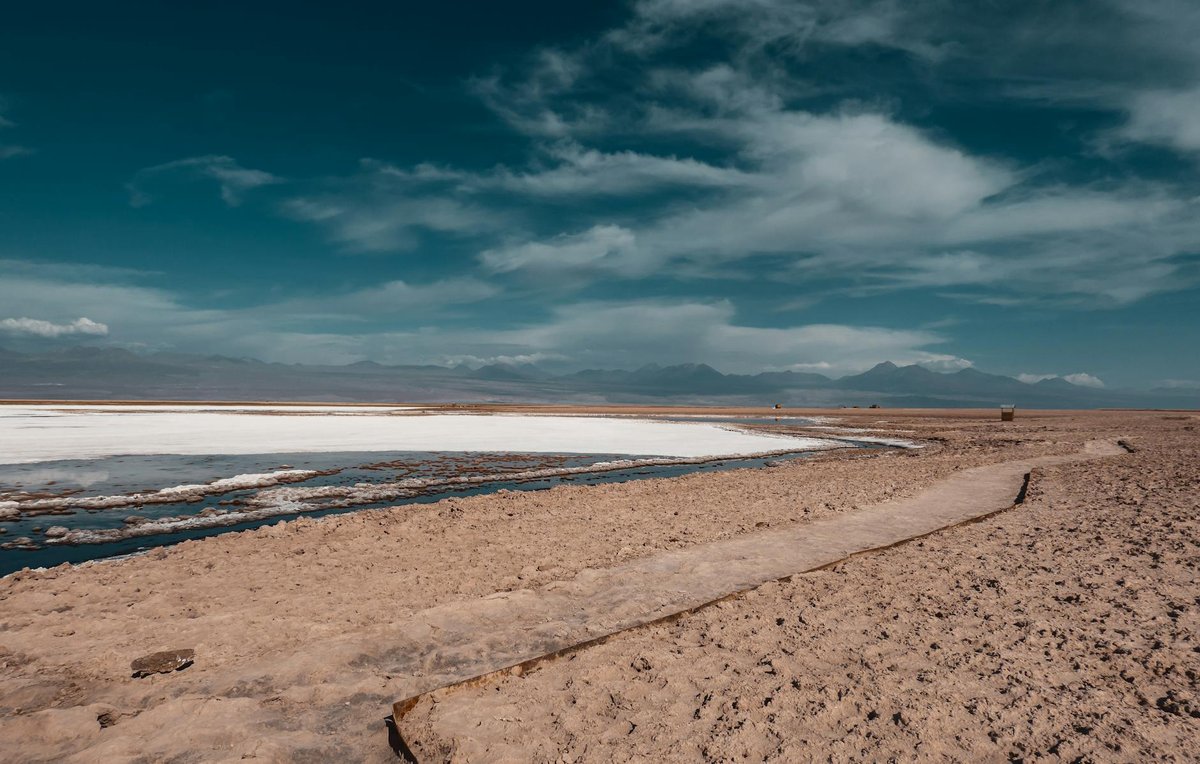 Arid desert landscape with salt flats stretching toward distant mountains in the Atacama