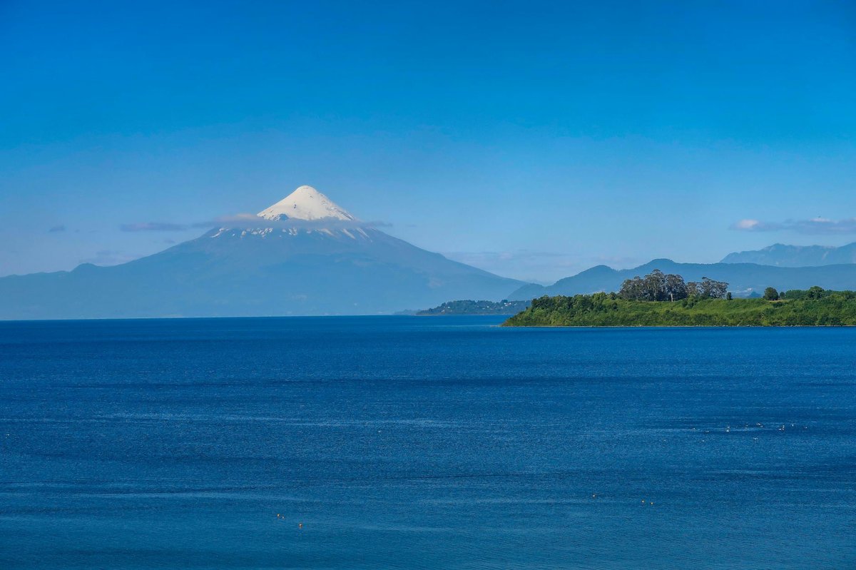 Snow-capped Osorno Volcano towering over Lake Llanquihue under clear blue sky in Chile Lake District