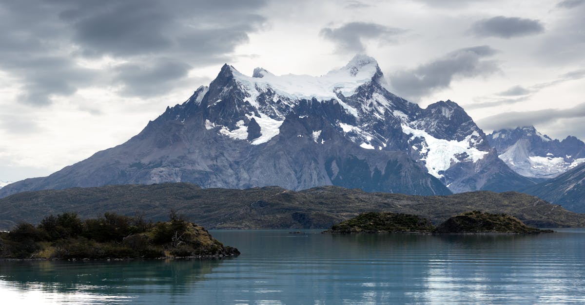 Dramatic landscape of Torres del Paine with snowy peaks and a serene lake under cloudy skies