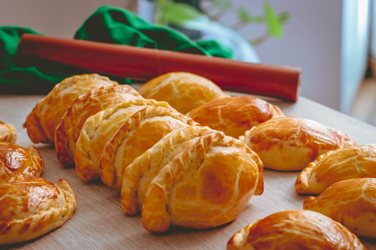 Freshly baked empanadas with golden brown crust on a wooden surface