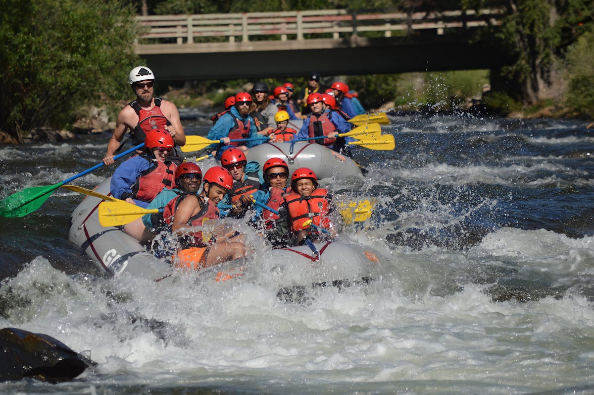 Whitewater rafting through rapids with mountain canyon backdrop