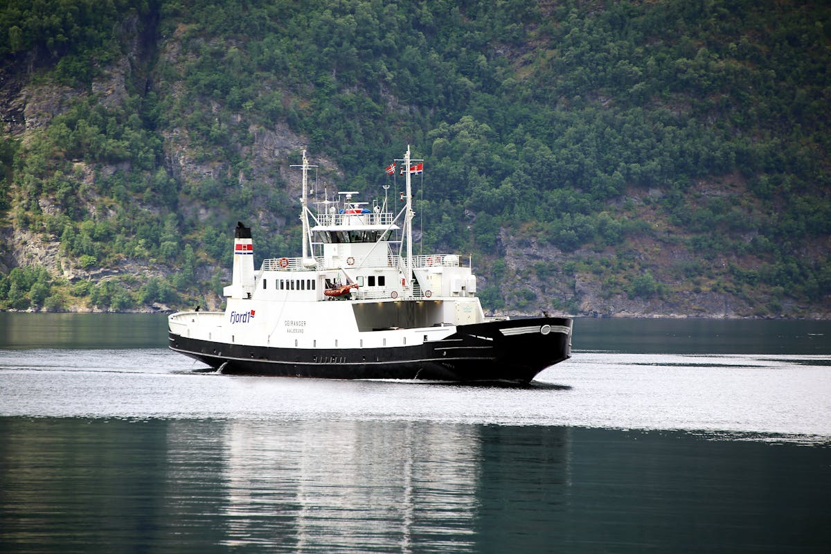 Ferry crossing through a fjord with green mountains on both sides