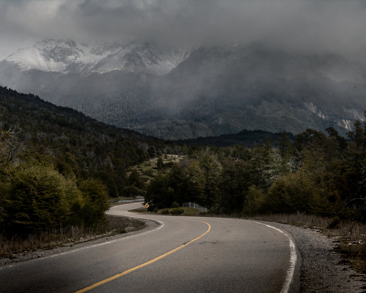 Curved road through misty mountains and green forest