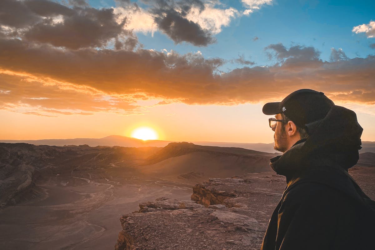 Traveler with backpack standing on a trail overlooking a dramatic mountain landscape in Chile