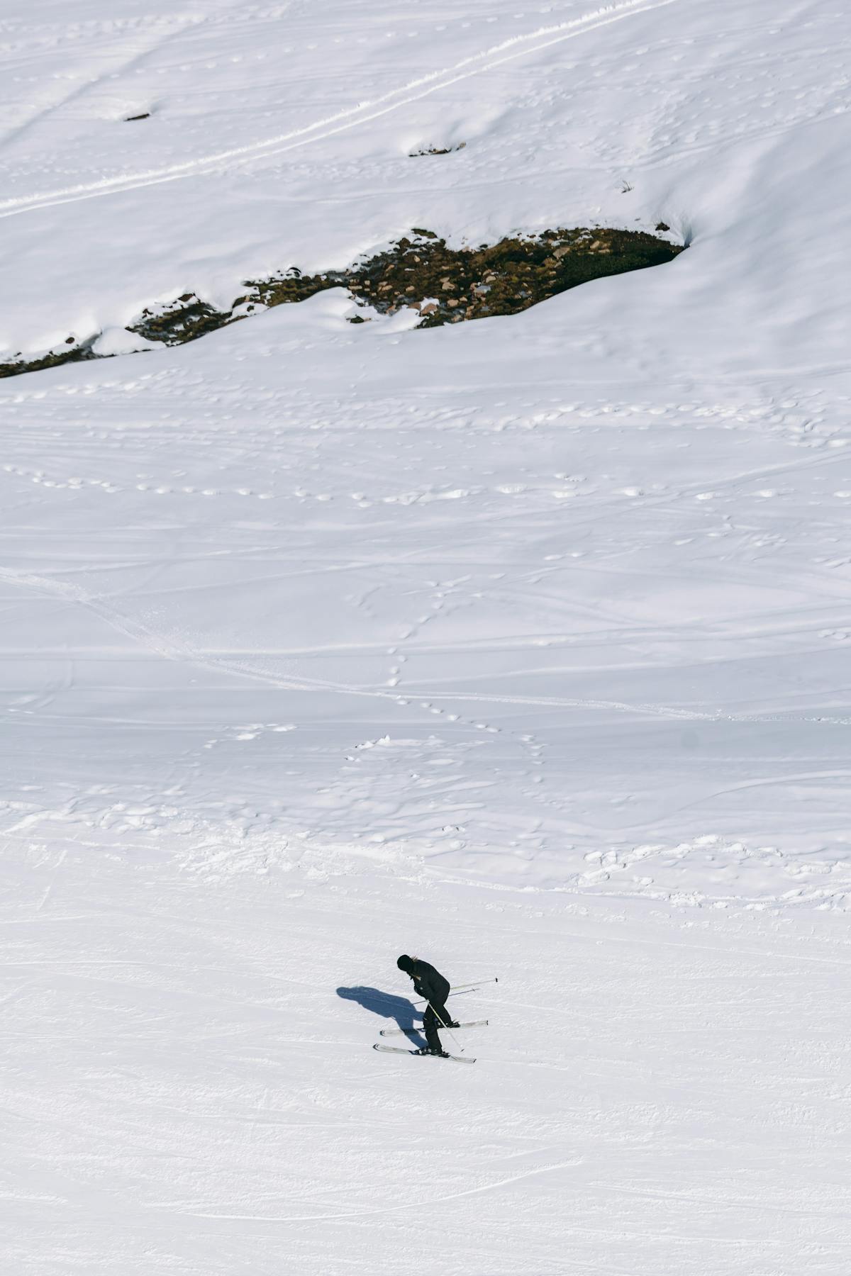 A lone skier navigating snowy slopes in the Chilean Andes under bright sunlight