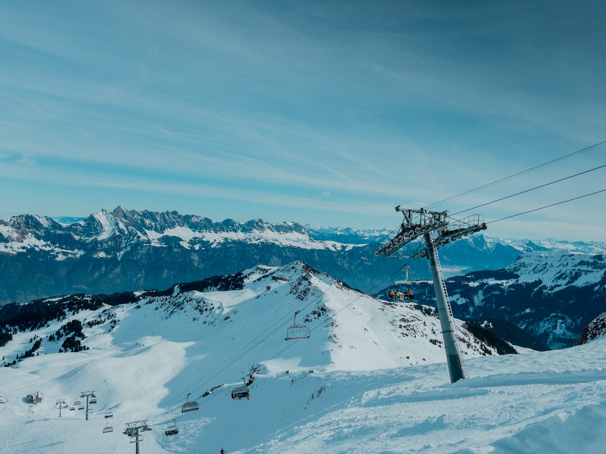 Ski lift ascending a snow-covered mountain range with clear blue sky