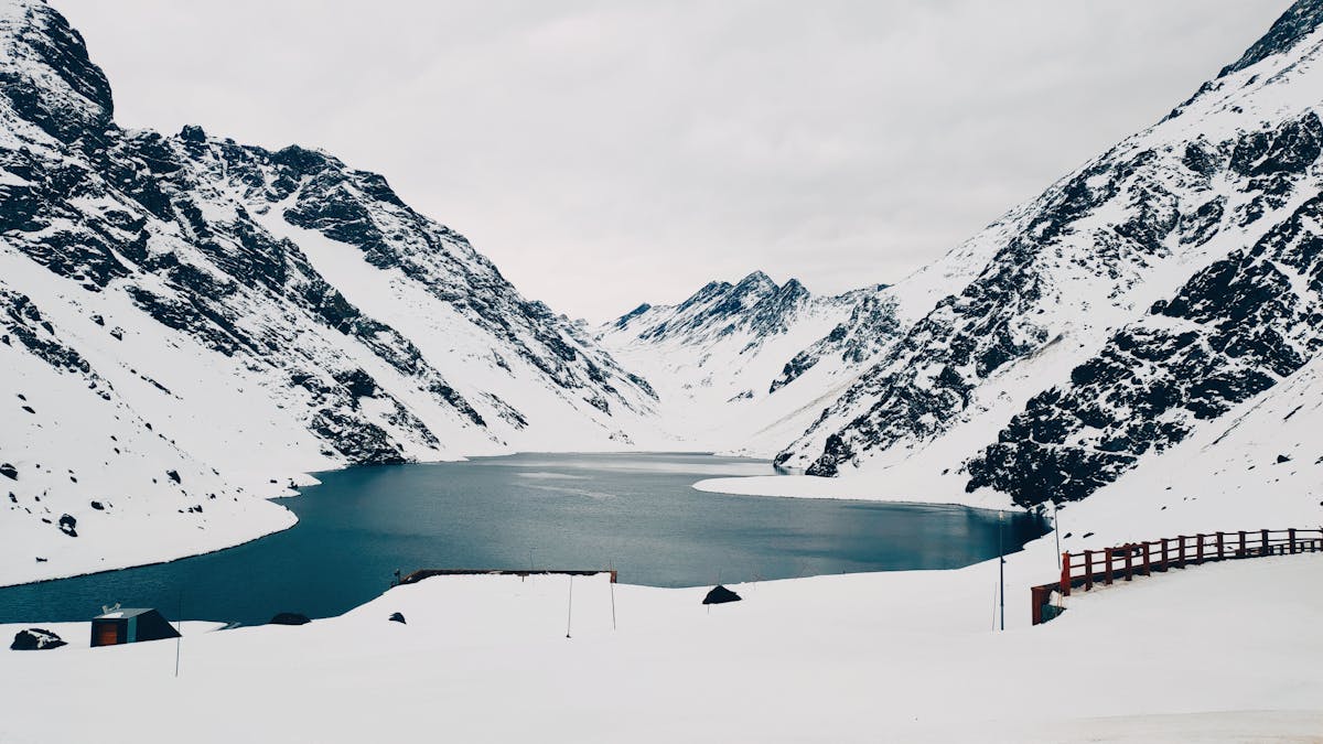 Snow-covered Andes mountains and serene lake at Portillo Chile