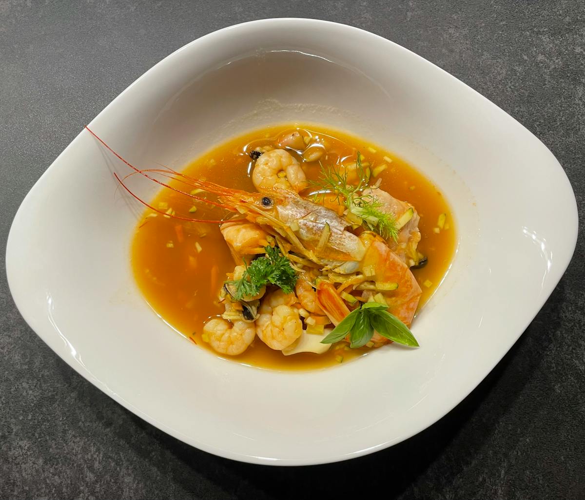 Seafood soup with fresh shrimp and fish in a rich golden broth