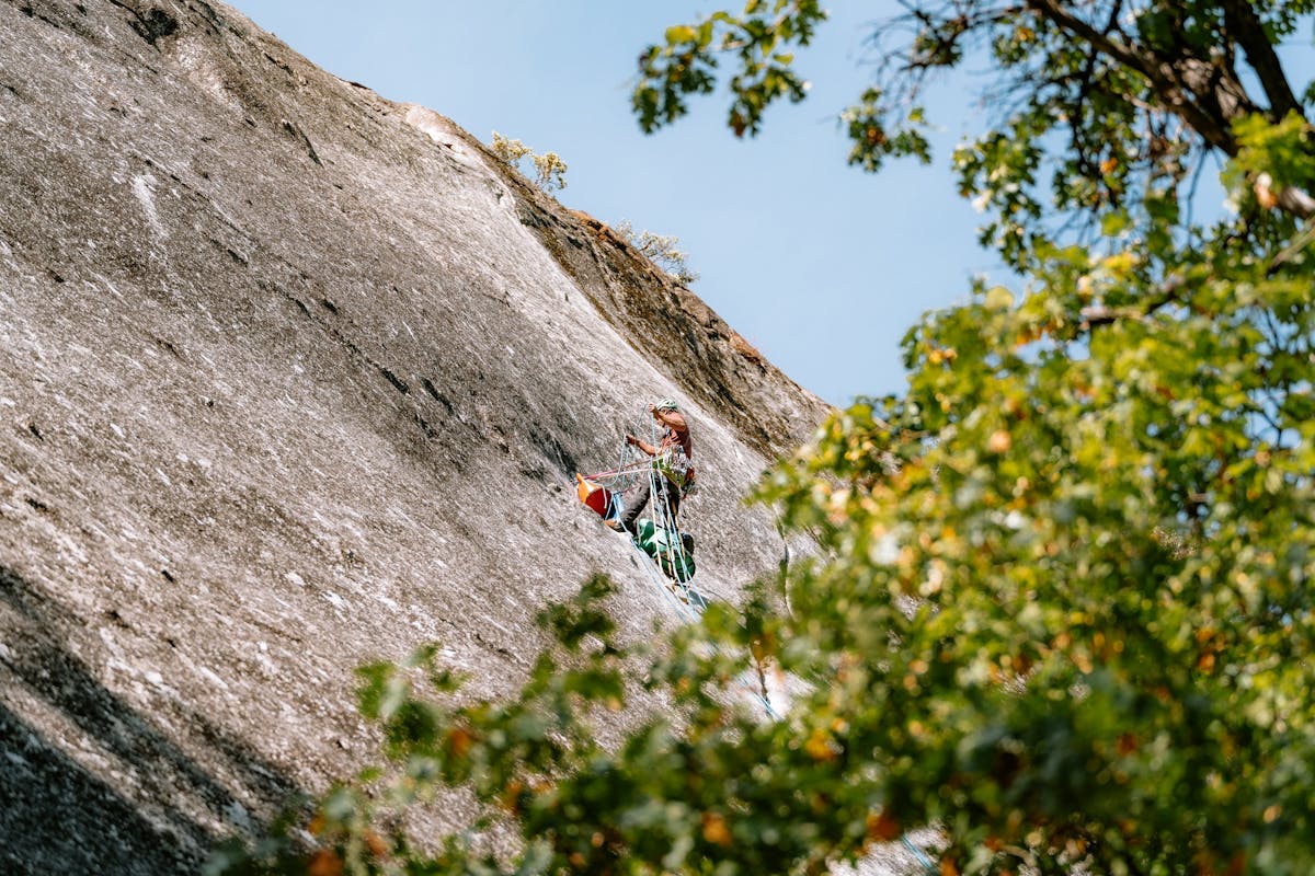 Rock climber navigating a challenging granite face in a mountain valley