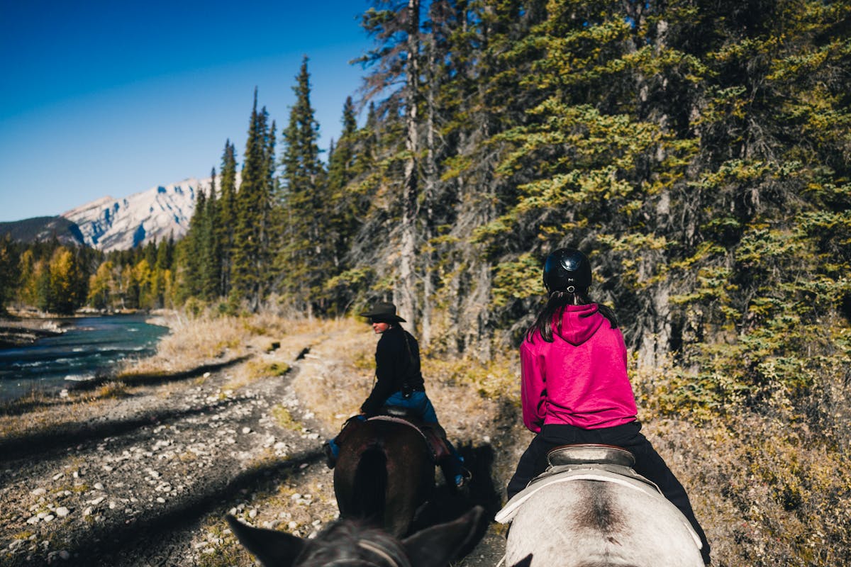 Horseback rider on a wilderness trail with river and mountains in the background