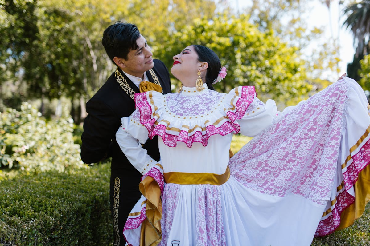 Couple performing a traditional dance in colorful clothing at an outdoor celebration
