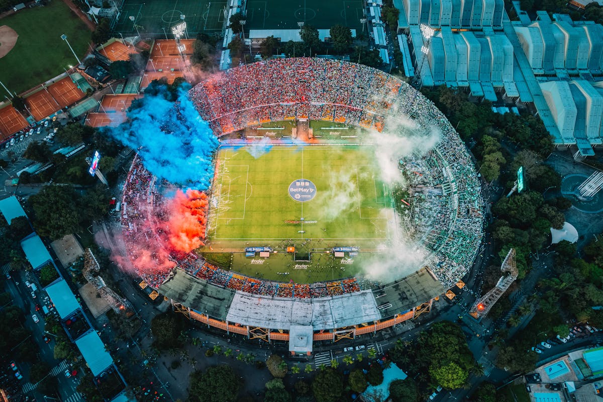 Aerial view of a packed football stadium with colorful smoke displays and fans