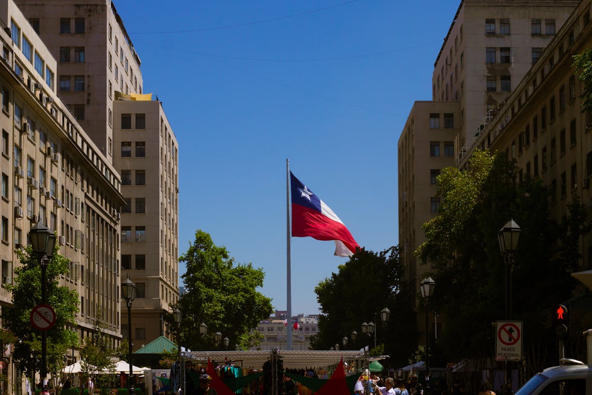 Chilean flag waving between historic buildings on a Santiago city street on a sunny day