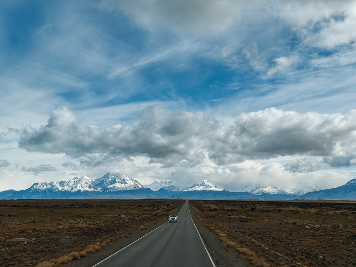 Long straight road leading toward snow-capped mountains in Patagonia under a wide open sky