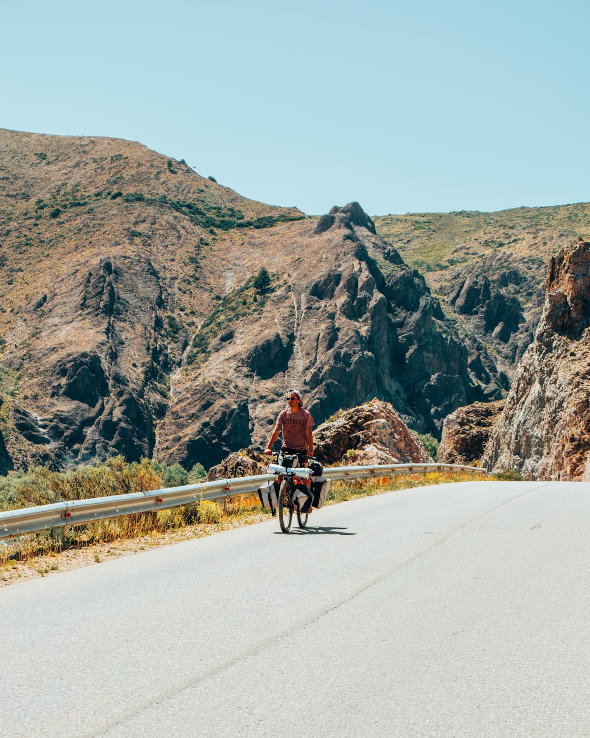 Cyclist riding on a scenic mountain road with rocky landscape and open sky