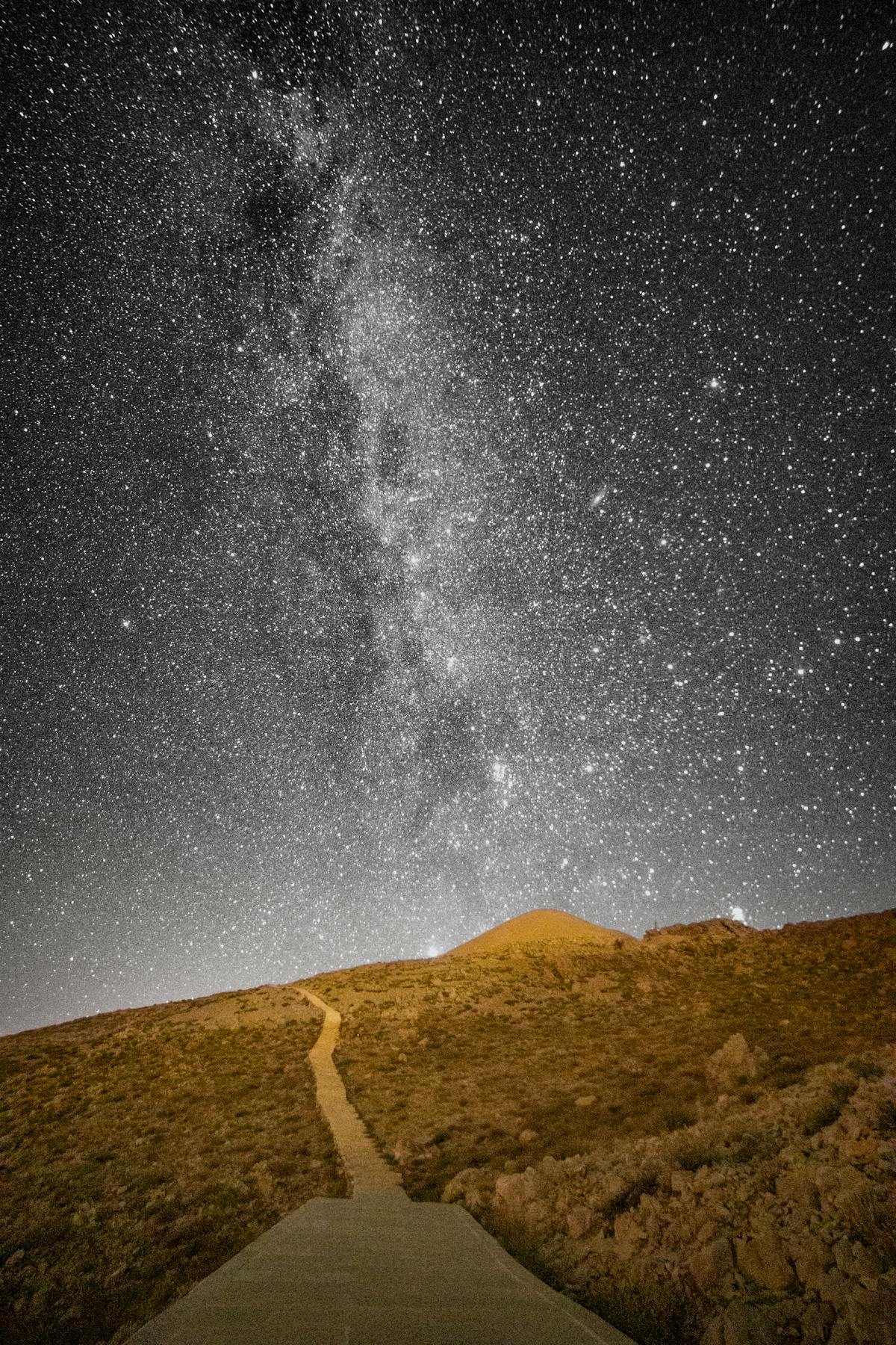 The Milky Way stretching across a clear desert night sky above a winding path
