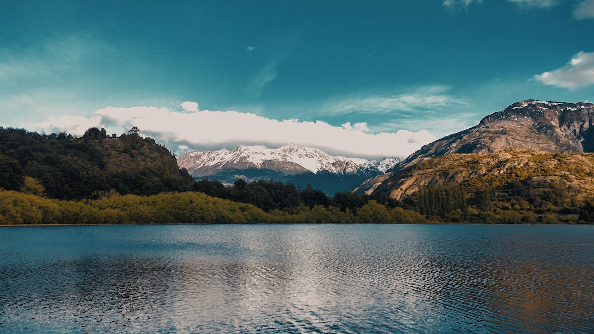 Calm turquoise lake with snow-capped mountains and green forest in Futaleufu, Chile