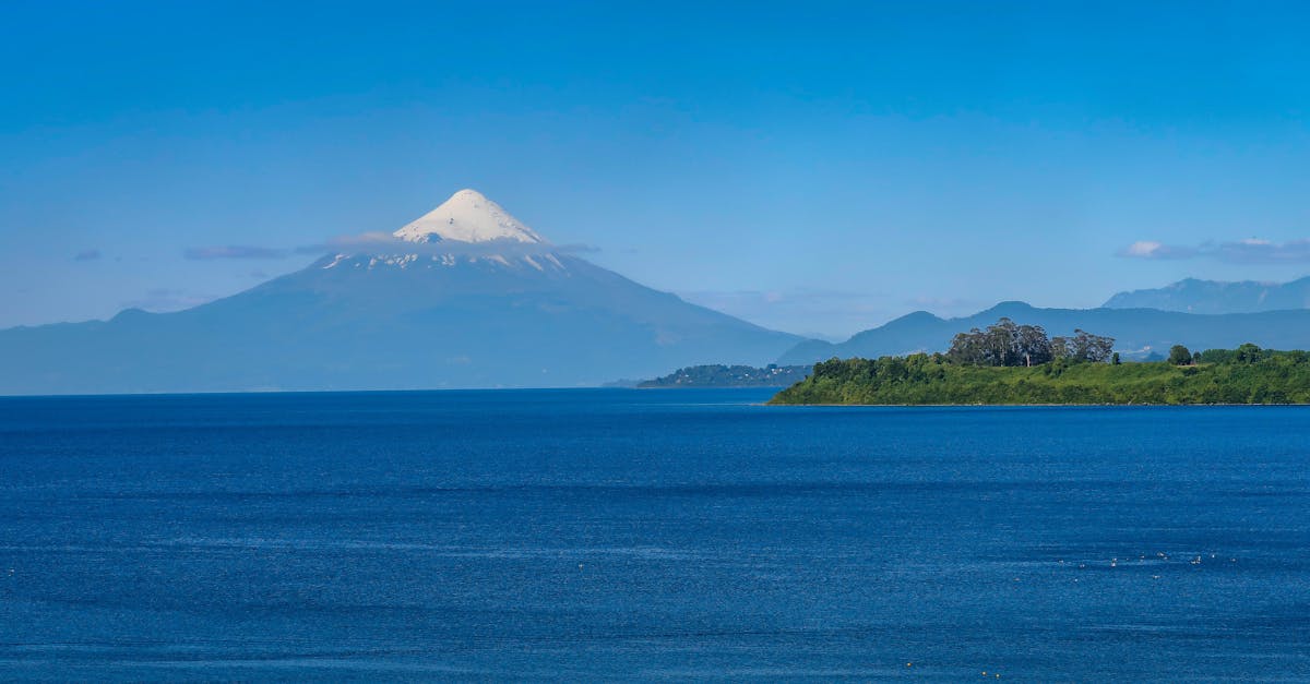 Osorno Volcano towering over Lake Llanquihue under a clear blue sky with green shores