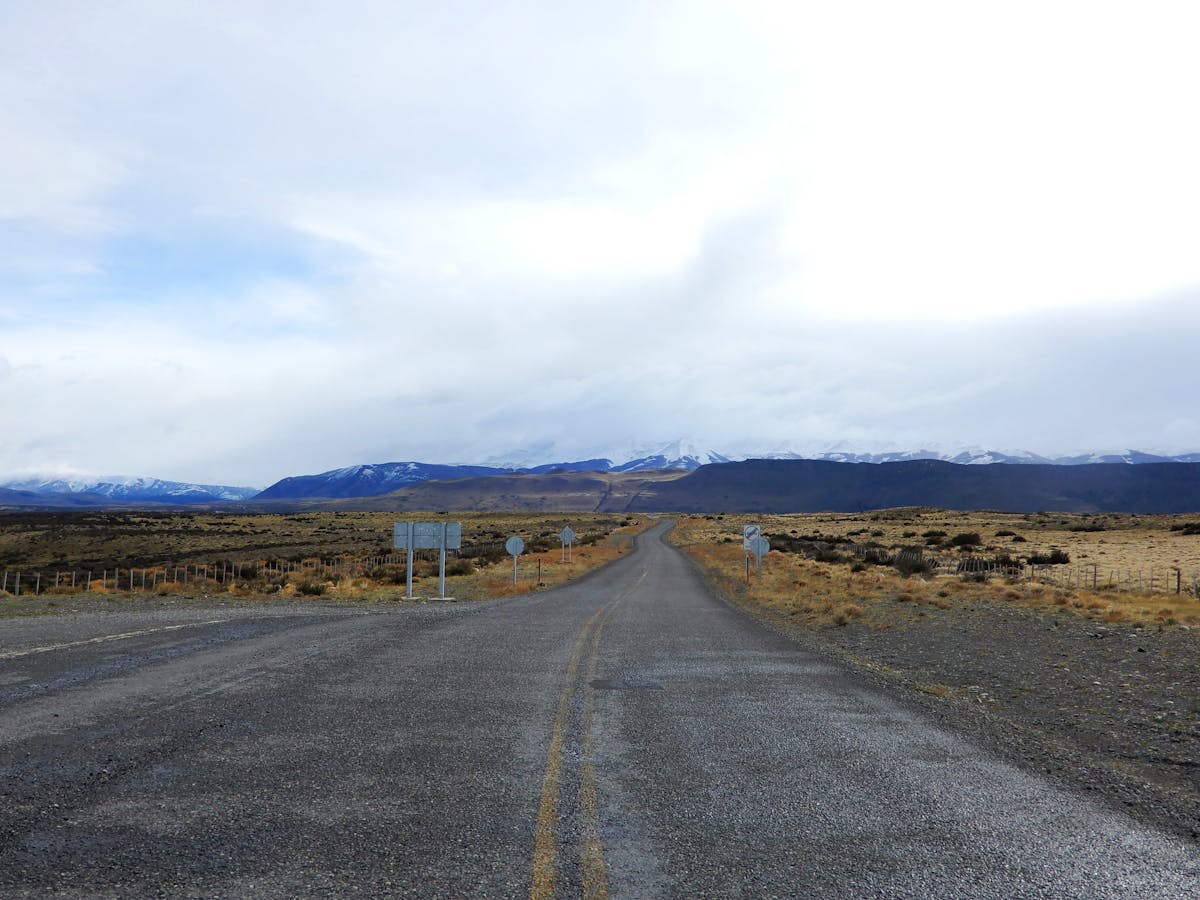 Empty road stretching toward Torres del Paine mountains under a vast sky