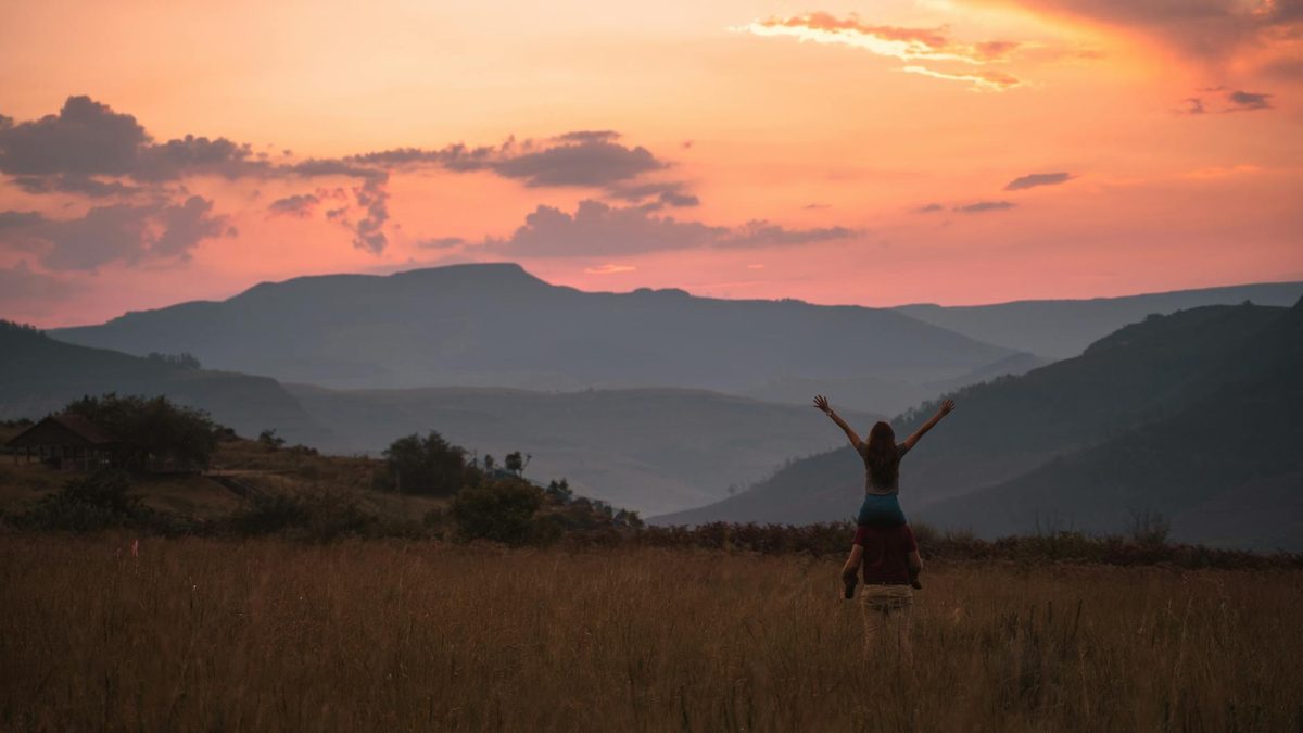 Couple watching a golden sunset over mountain scenery