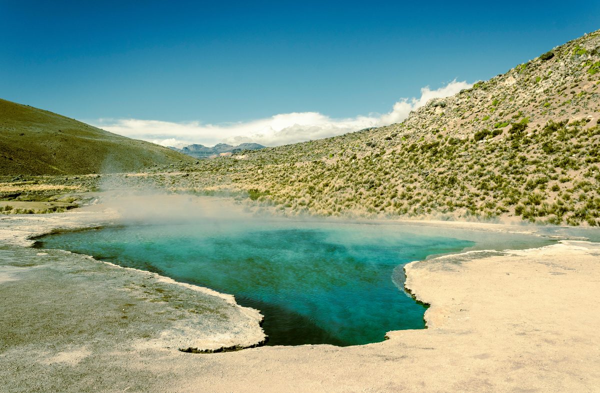 Calm hot spring with clear blue water surrounded by arid desert hills