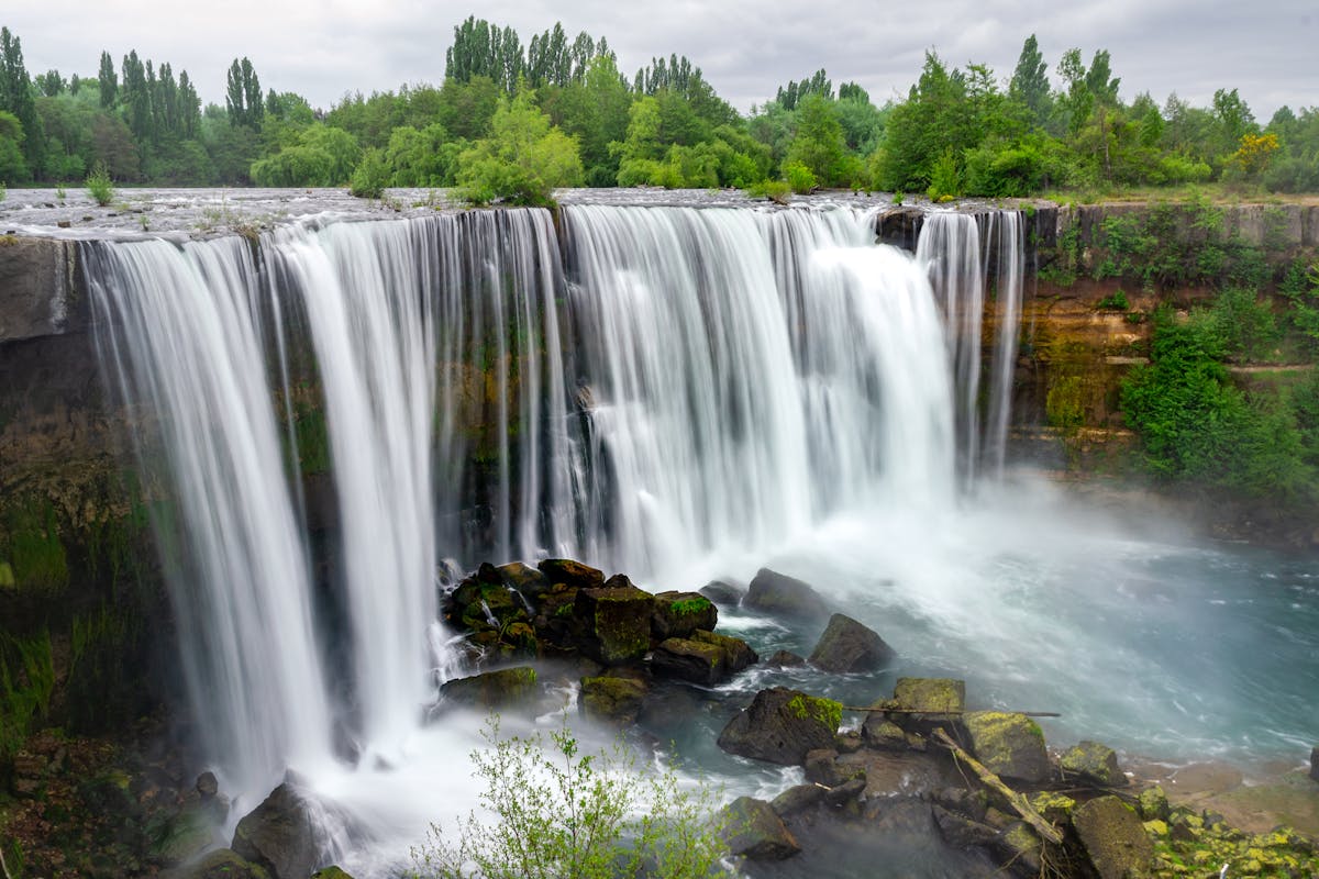 Turquoise waterfall cascading through lush green forest in southern Chile