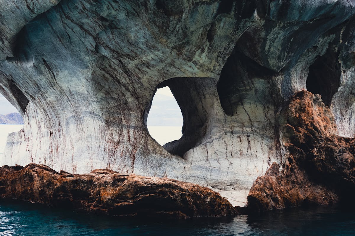 Natural marble archway formation over calm turquoise water in Patagonia