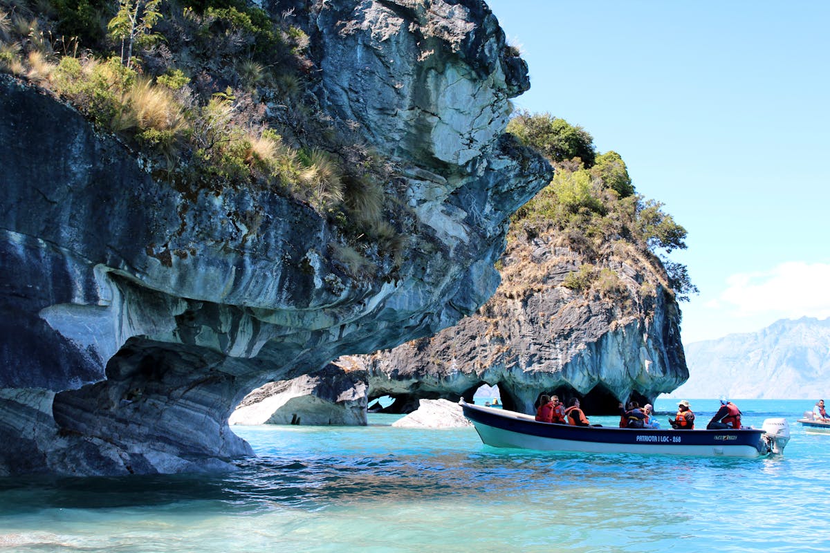 Boat approaching the Marble Caves on a sunny day with turquoise water at Puerto Rio Tranquilo