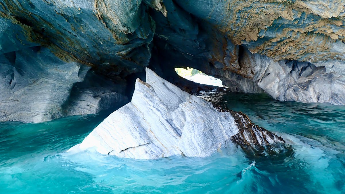 Close-up of marble cave formations with smooth curved walls above turquoise water