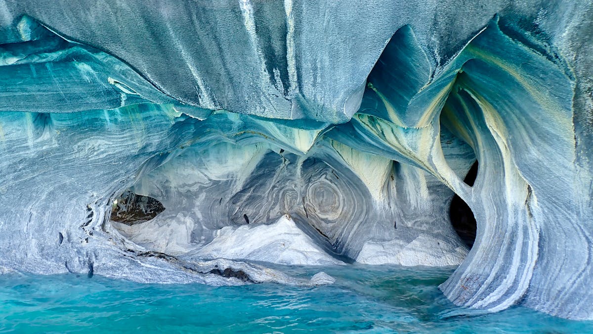 Inside the marble caves showing smooth eroded walls and turquoise water reflections