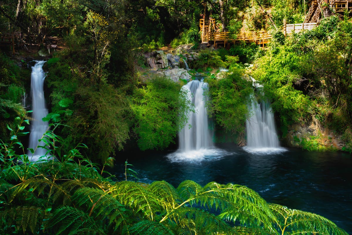 Cascading waterfalls surrounded by lush green forest near Pucon, Chile
