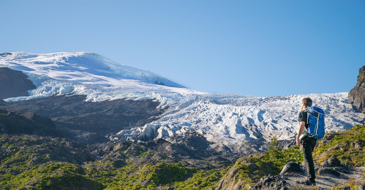 Lone hiker with backpack admiring snow-capped glacier in the Patagonian mountains under clear sky
