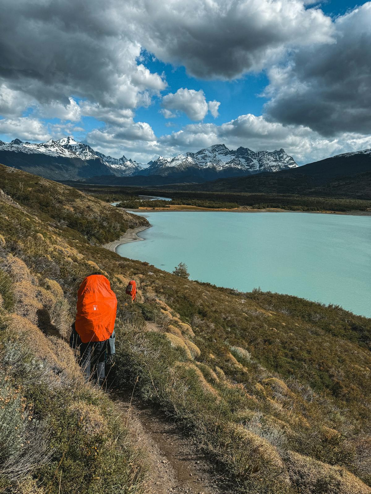 Hikers with backpacks trekking along a lakeside trail in Chilean Patagonia