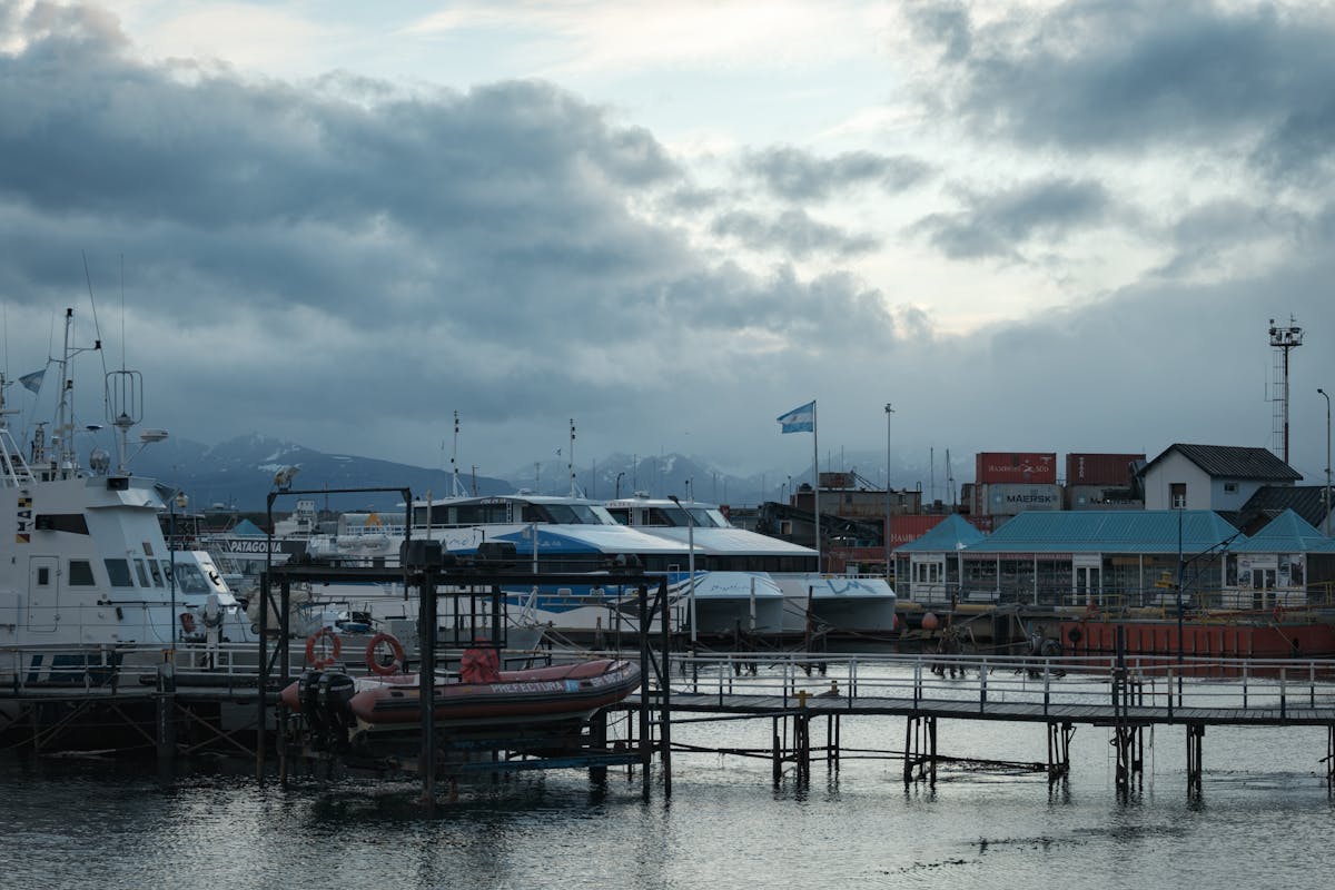 Boats docked at Ushuaia harbor with snow-capped mountains in background