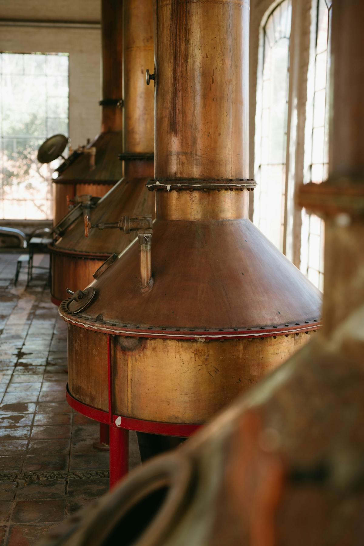 Close-up of copper pot stills inside a traditional distillery with warm lighting