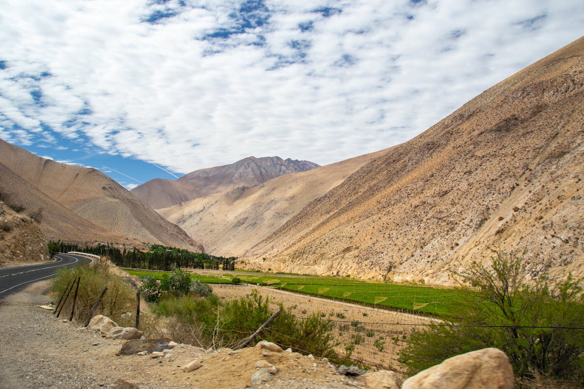 Breathtaking valley landscape in Pisco Elqui, Chile with brown mountains and green agricultural fields under a dappled sky