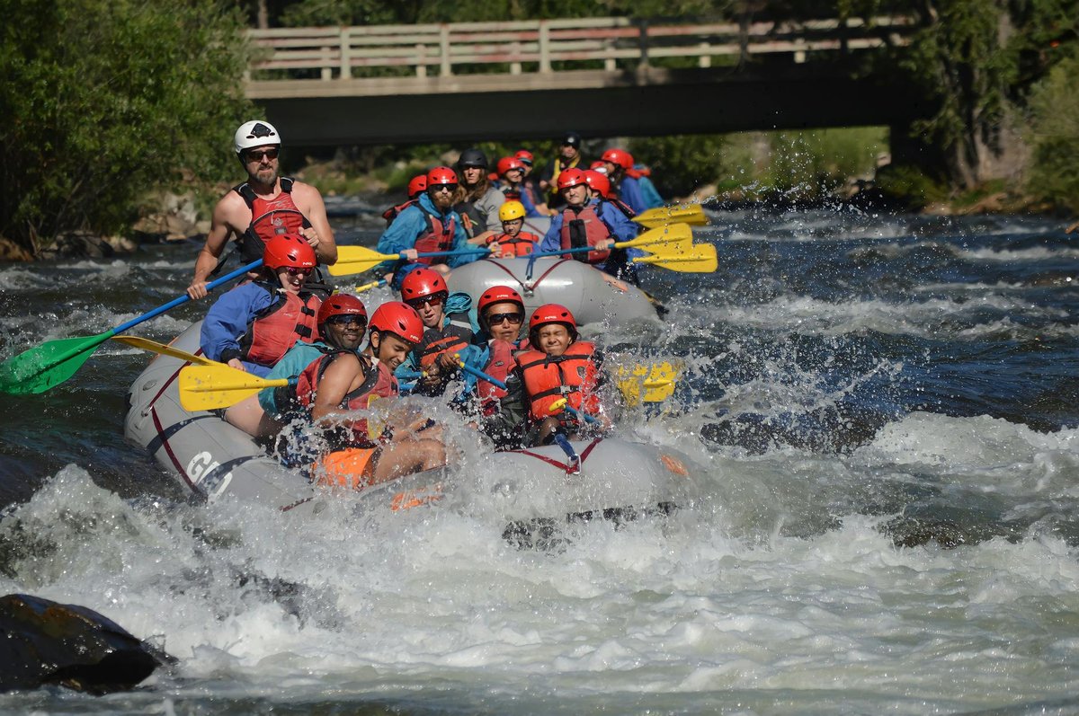 Group whitewater rafting through rapids with paddles