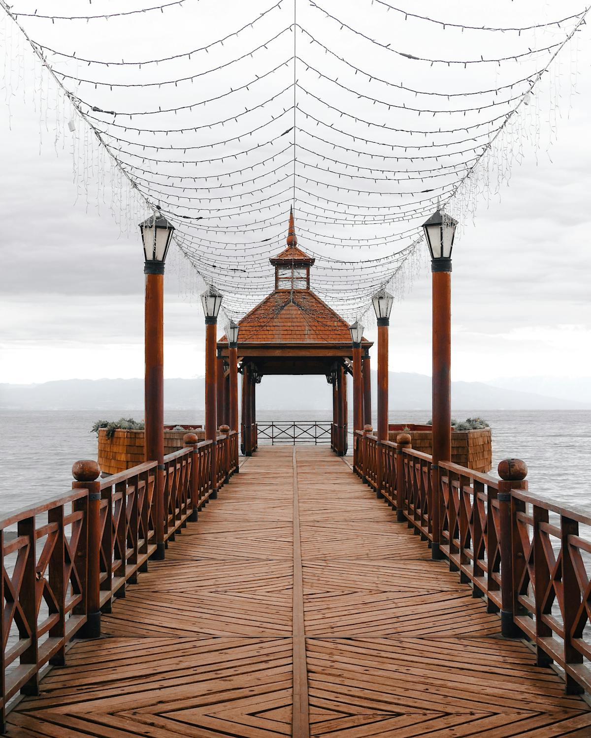 Charming wooden pier with canopy lights on Lake Llanquihue at dusk in Puerto Varas, Chile