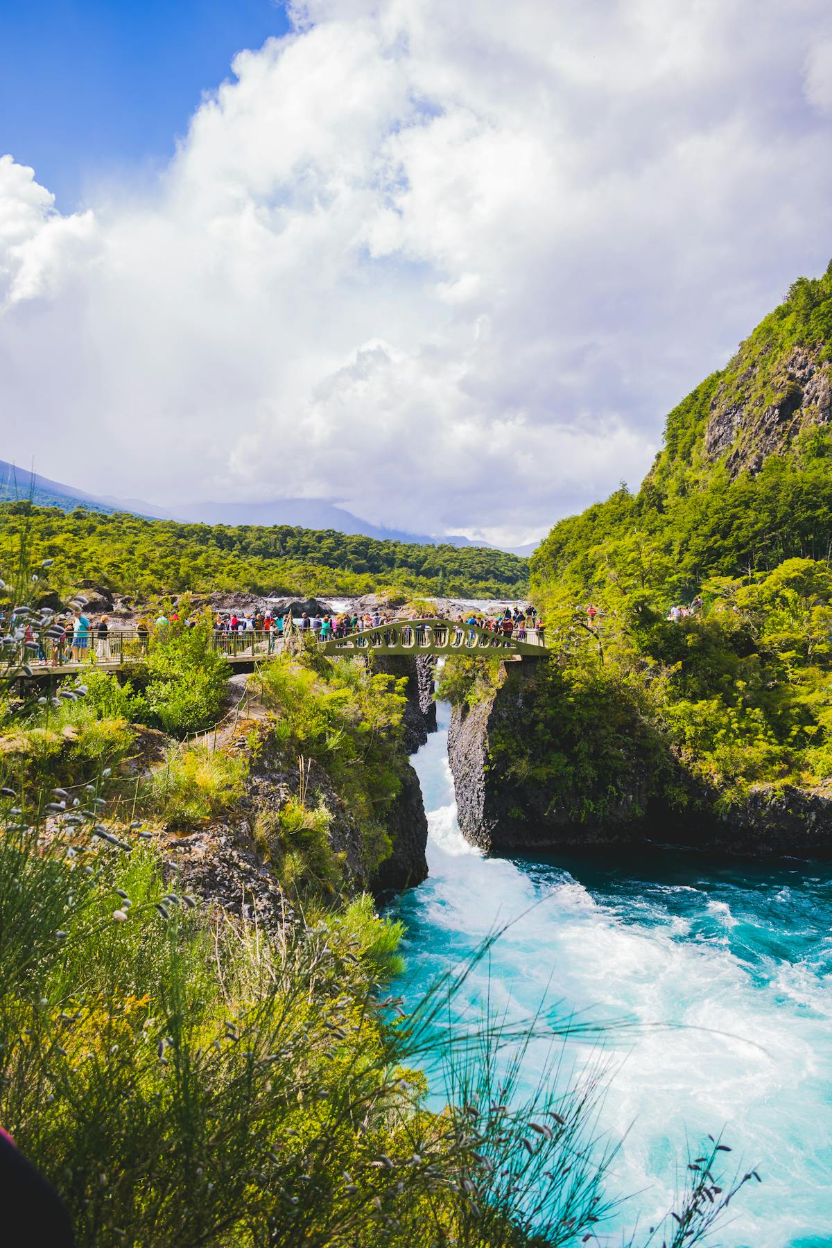 Petrohue Waterfalls with a bridge overlooking the cascading blue-green water in Los Lagos, Chile