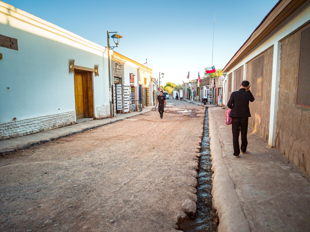 Traditional adobe street in San Pedro de Atacama with people walking in the warm afternoon light