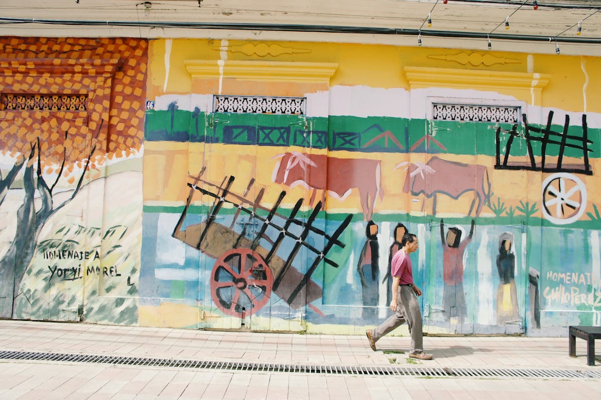 Street mural in Santiago depicting cultural themes with a person walking past