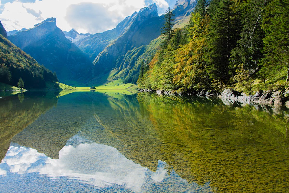 Turquoise mountain reservoir surrounded by snow-capped Andes peaks under clear sky