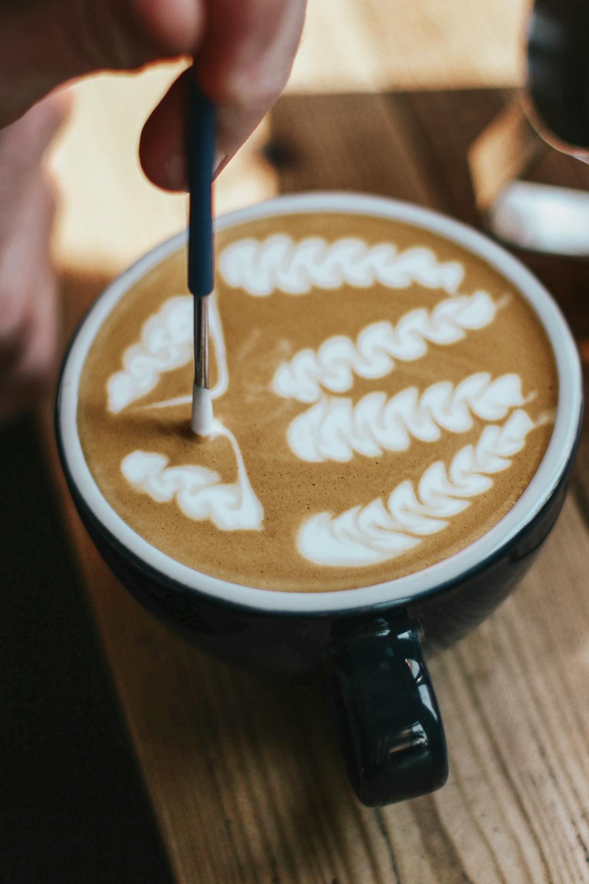Barista crafting intricate latte art in a coffee cup at a specialty coffee shop