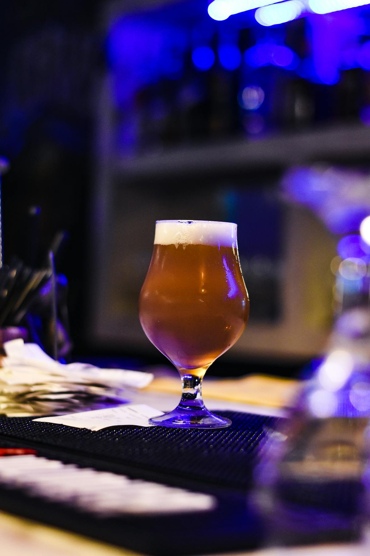 Glass of craft beer on a bar counter with ambient blue lighting