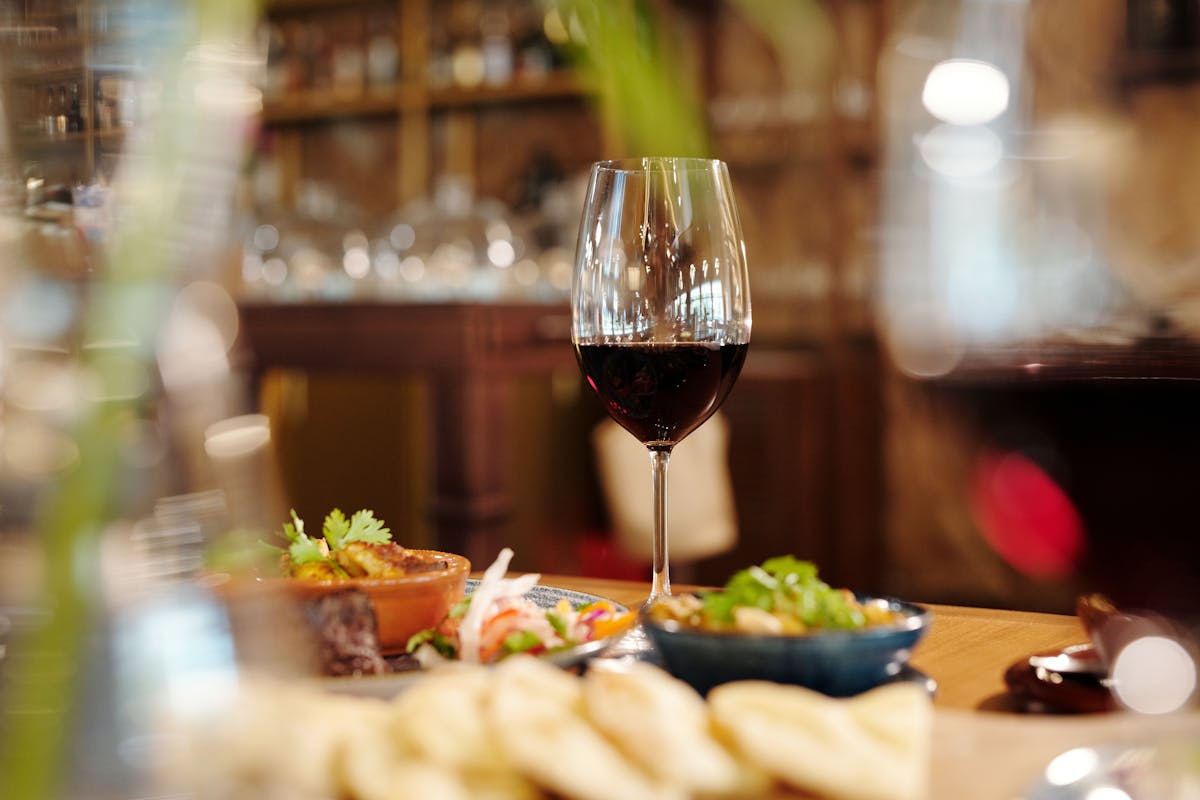 Glass of red wine alongside appetizing dishes at a restaurant table