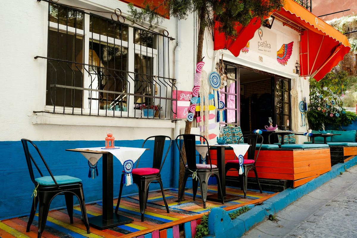 Colorful outdoor cafe tables and chairs on a tree-lined street