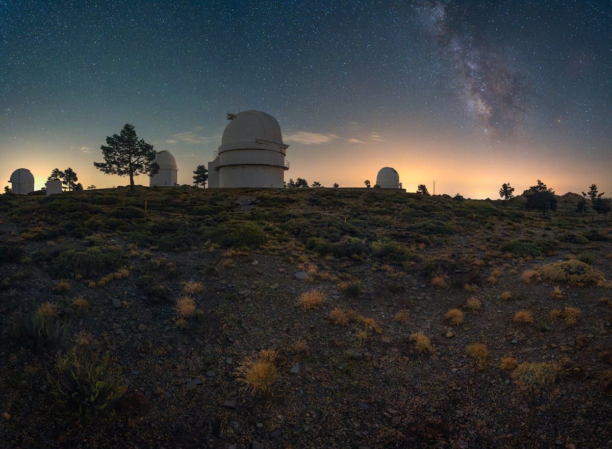 Observatory domes under a starry night sky on a mountain plateau used for astronomical research