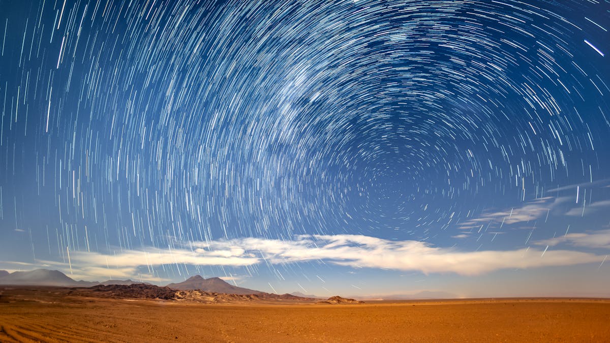 Long exposure star trails circling over the Atacama Desert mountains at night