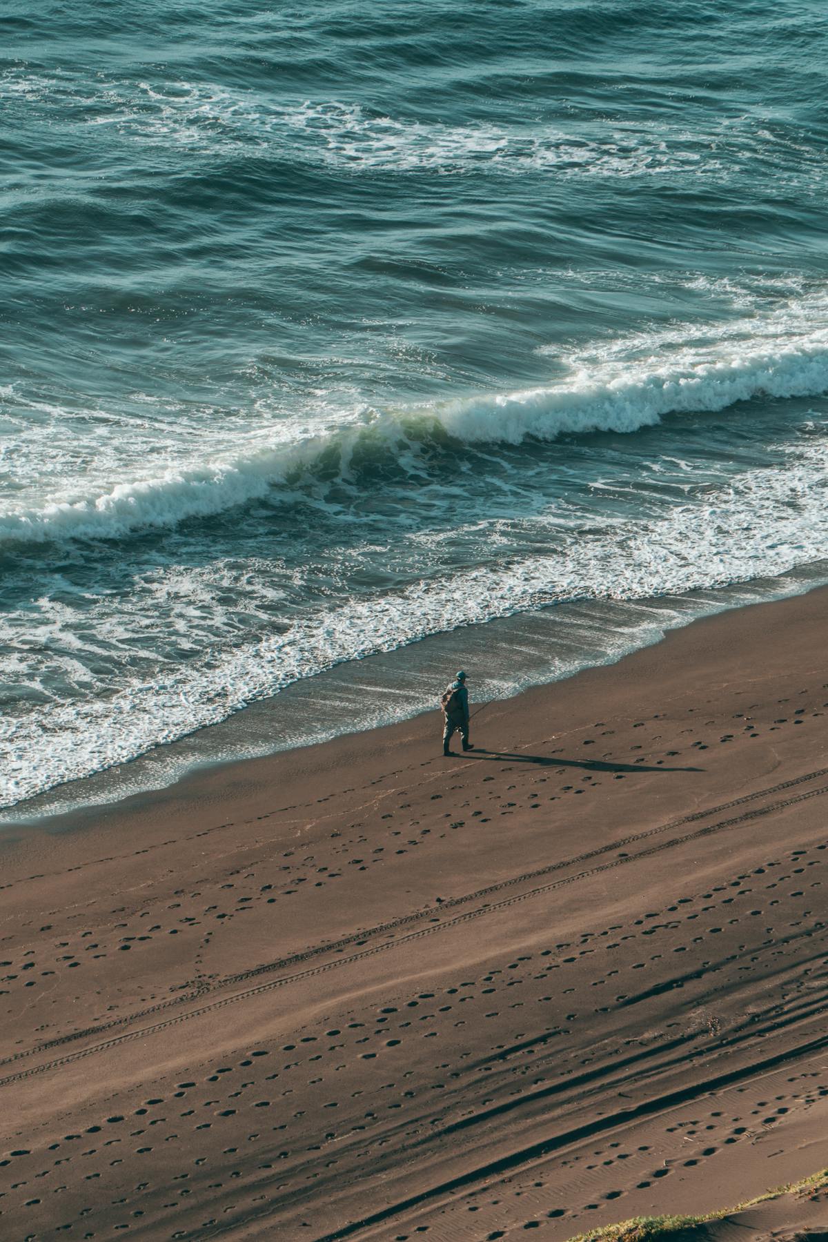 A lone figure walks along the scenic Matanzas beach in Chile with waves crashing