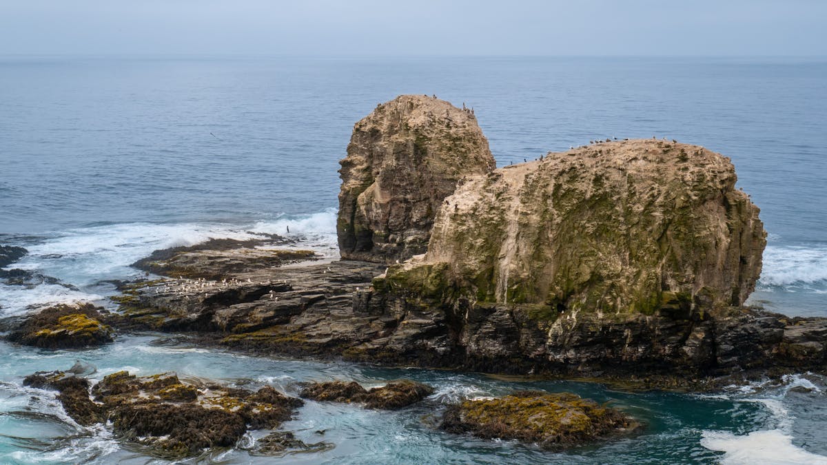 Rocky coastline of Pichilemu, Chile with ocean waves crashing against dark rocks